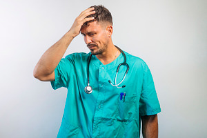 Frustrated Doctor Touching Head with Hand, a Person Photo by karrastock