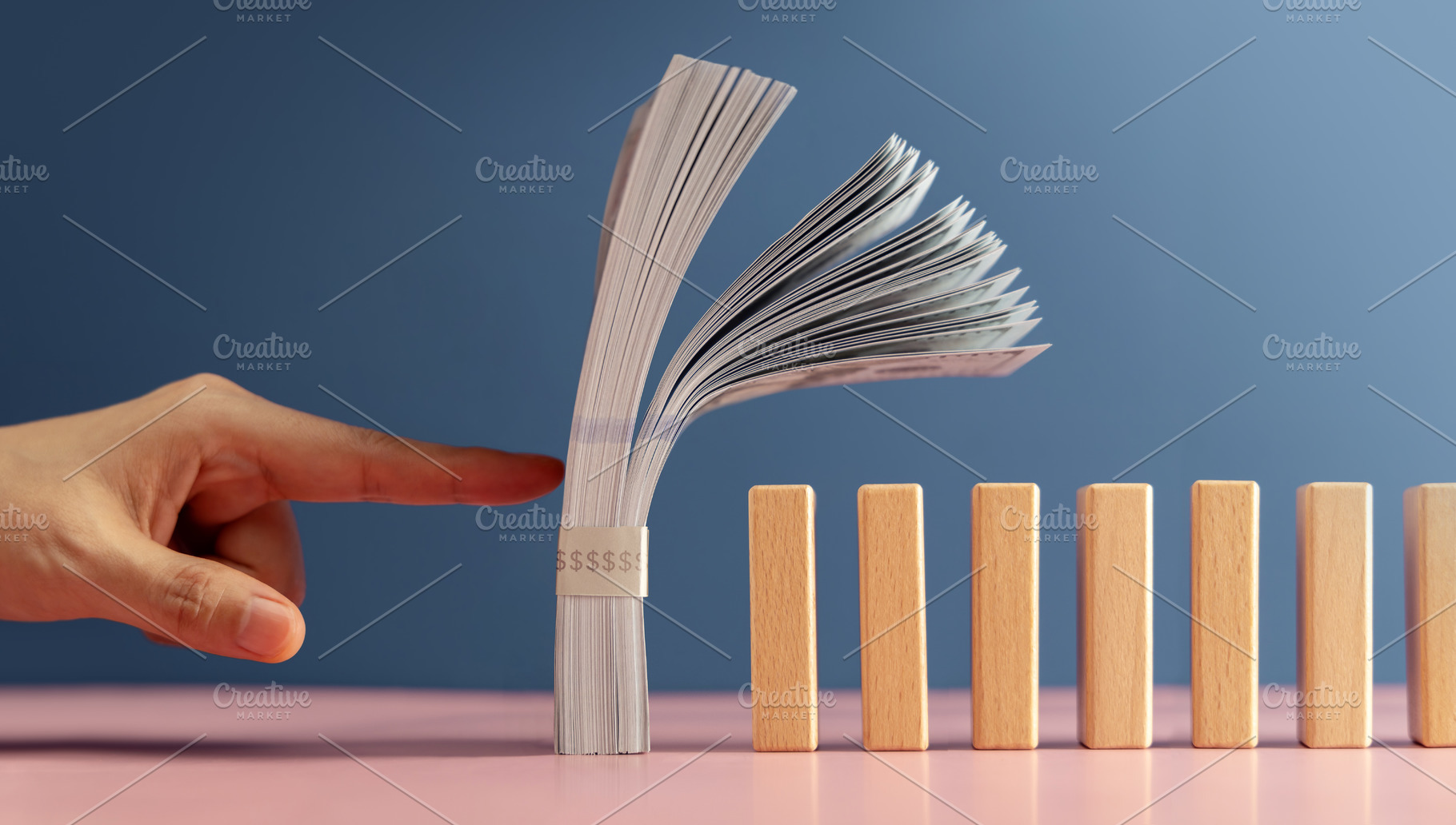 A finger about to push US dollar stack onto dominos, symbolizing, a Photo by salmon.black
