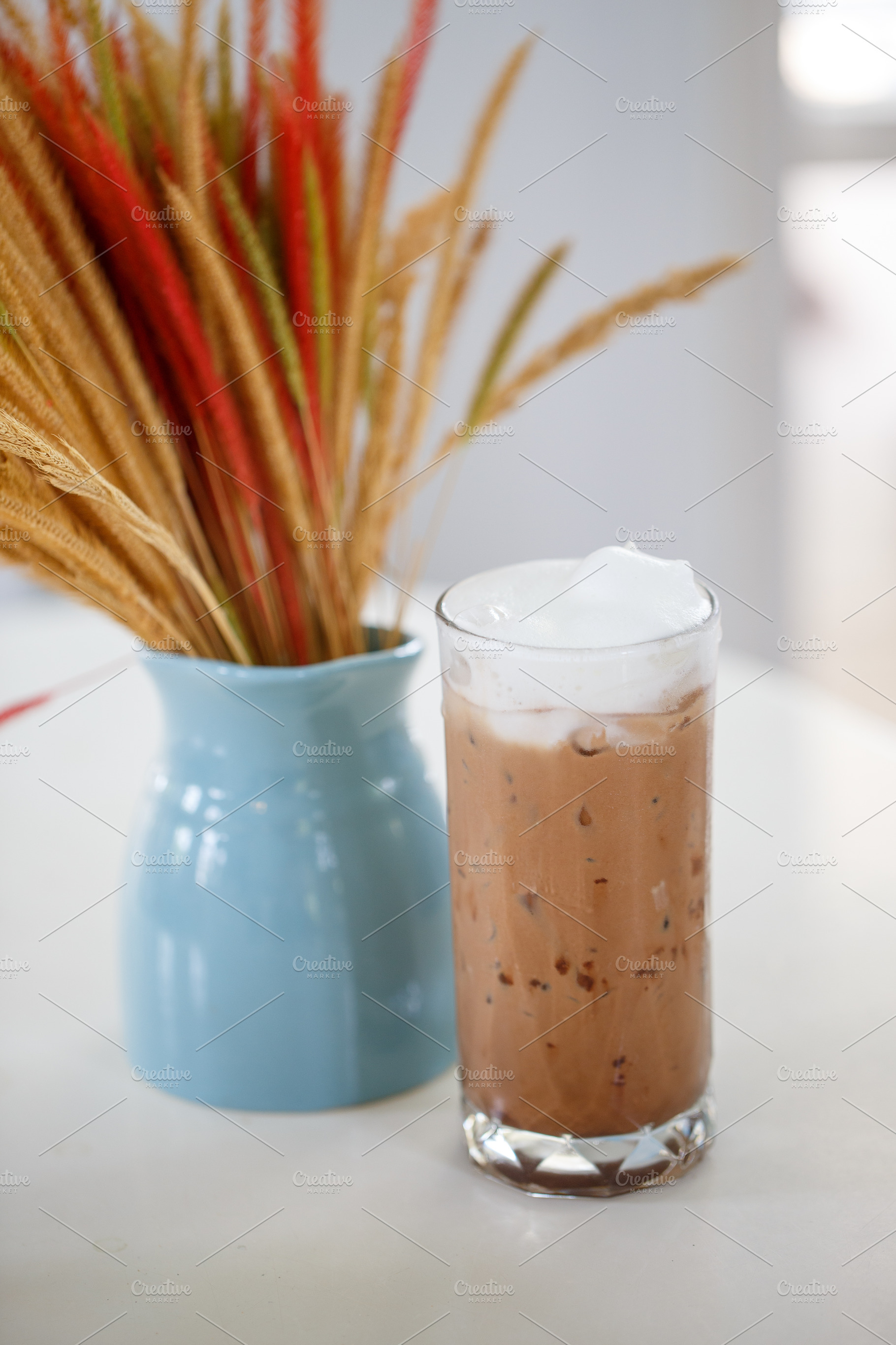 Refreshing iced drink with whipped cream beside decorative plant, a Food & Drink Photo by a454