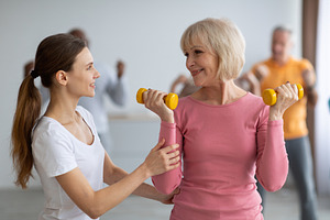 Fitness instructor assisting multiracial group of elderly people, a Photo by Prostock-Studio