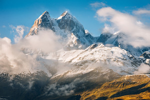 Snowy peak with clouds containing adventure, altitude, and autumn