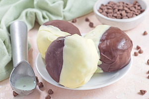 Dark and white chocolate covered ice cream sandwiches, on white plate, horizont, a Food & Drink Photo by iuliia_n