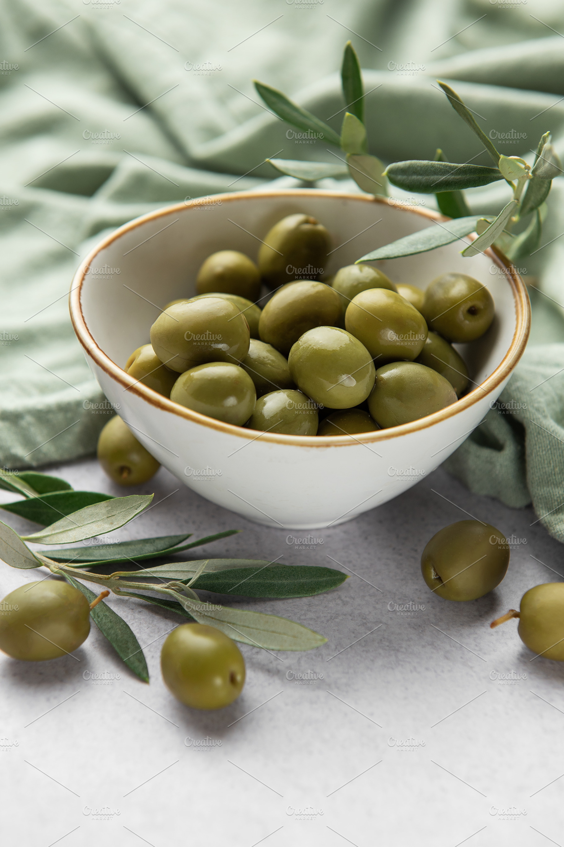 Fresh green olives with olive branches in a bowl, displaying med, a Food & Drink Photo by Olena Rudo