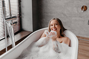 Young pretty woman relaxing in bathtub, playing and blowing foam, looking and s, a Photo by Prostock-Studio (Thumbnail 2 of 2)