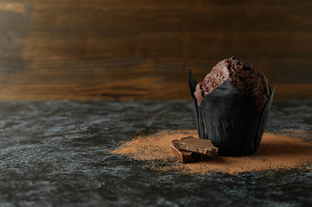 Tasty chocolate muffin on black smokey table, a Food & Drink Photo by AtlasStudio