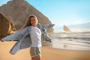 Happy woman standing with arms outstretched on seashore at beach, a Person Photo by andreonegin market