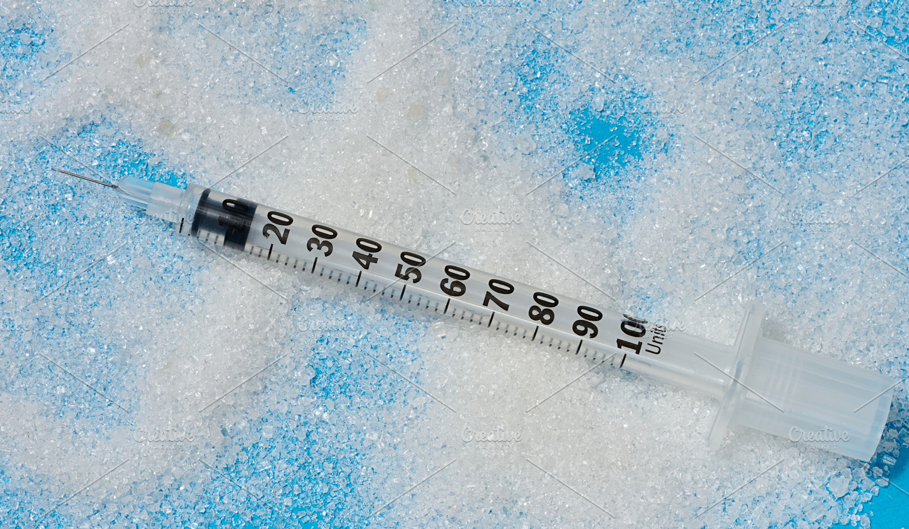An insulin syringe with an open needle lies on scattered white s, a Health & Medical Photo by ndanko