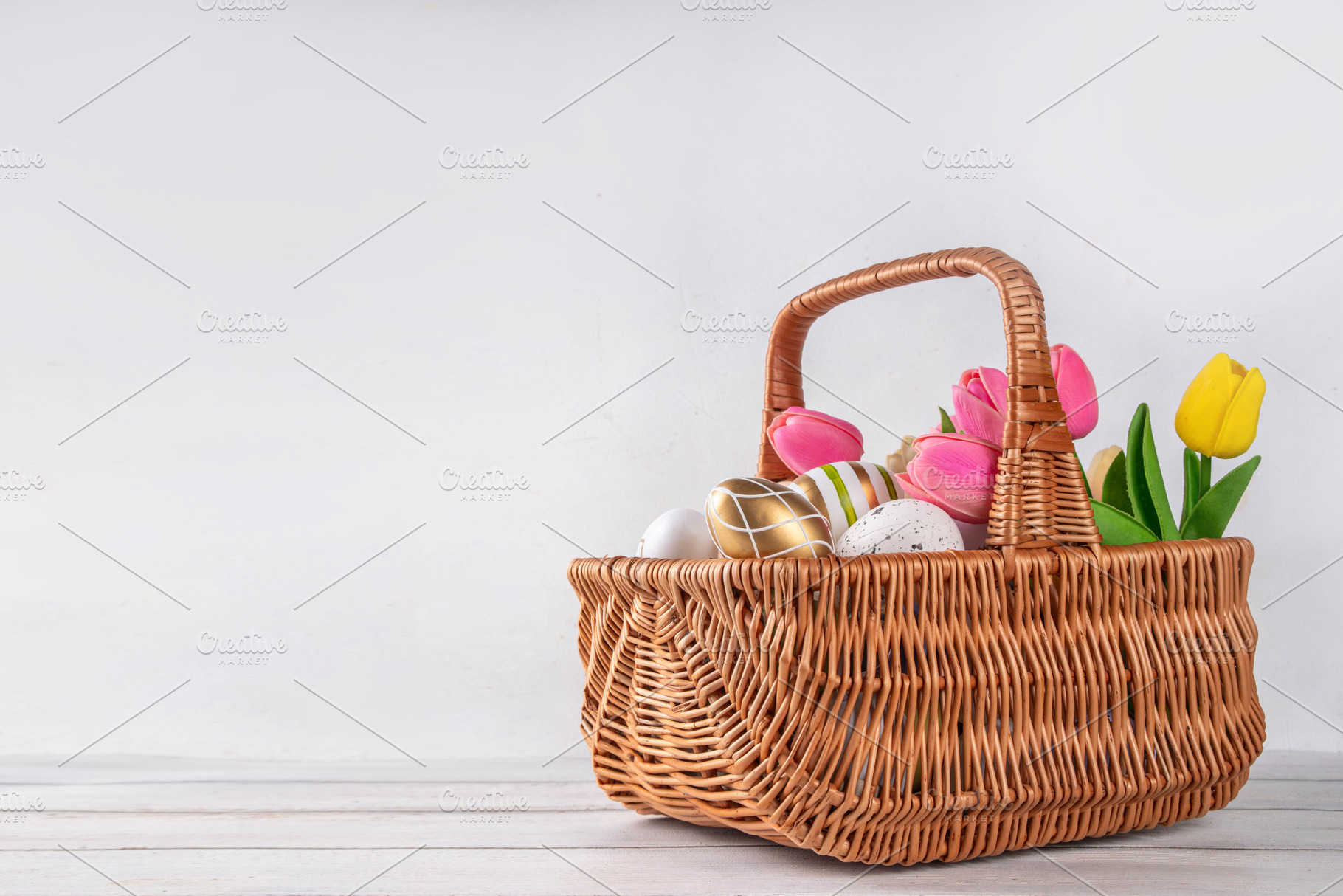 Easter eggs and tulips flowers in basket on wooden background, a Holiday Photo by Rimma