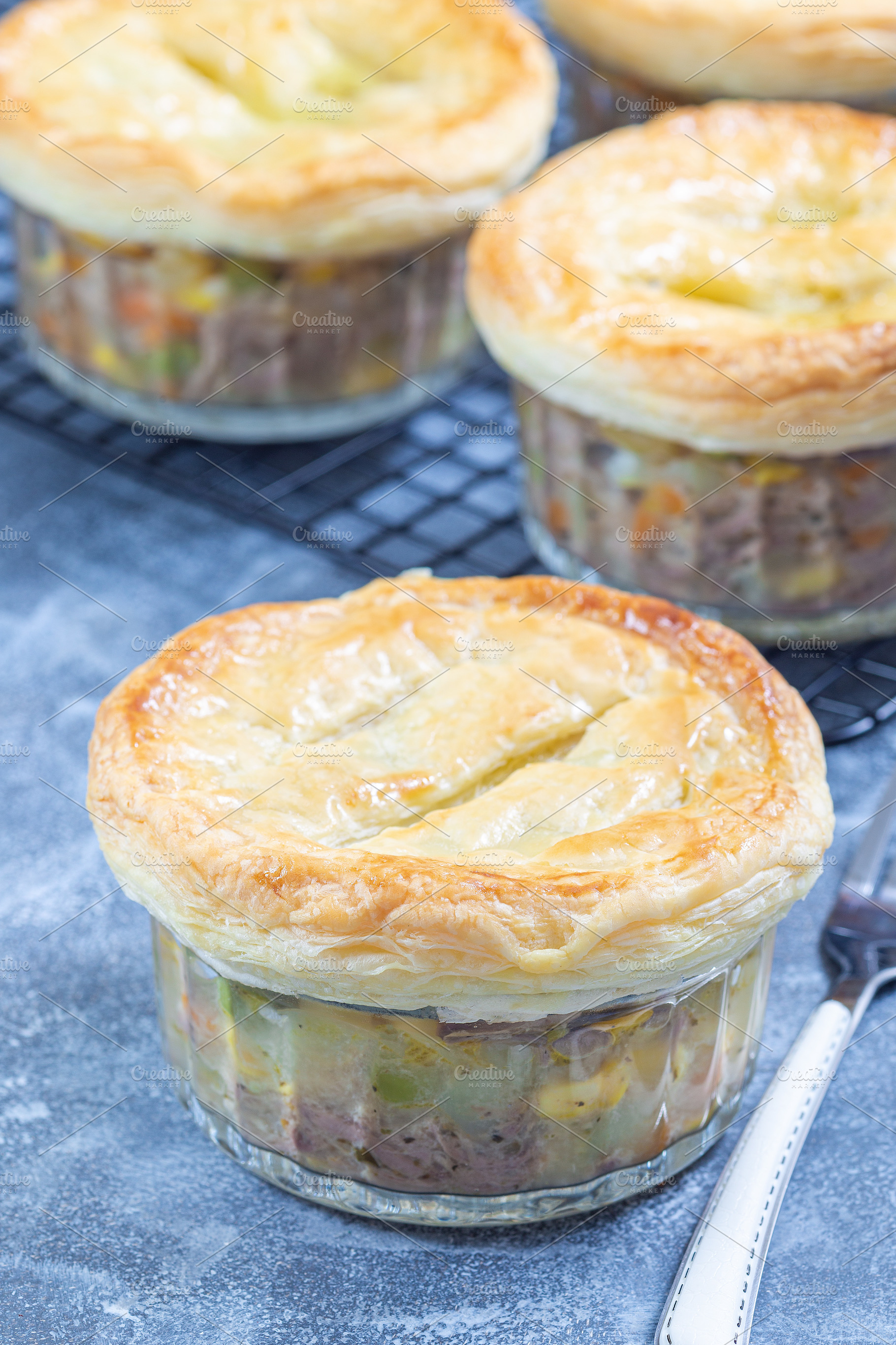 Individual beef pot pies or deep dish pies in ramekin and on cooling rack, vert, a Food & Drink Photo by iuliia_n