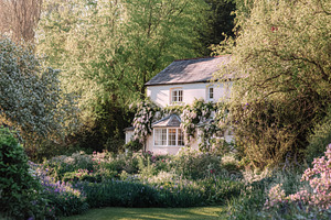 Idyllic cottage house nestled in lush green garden during spring, a Photo by Studio ANNA