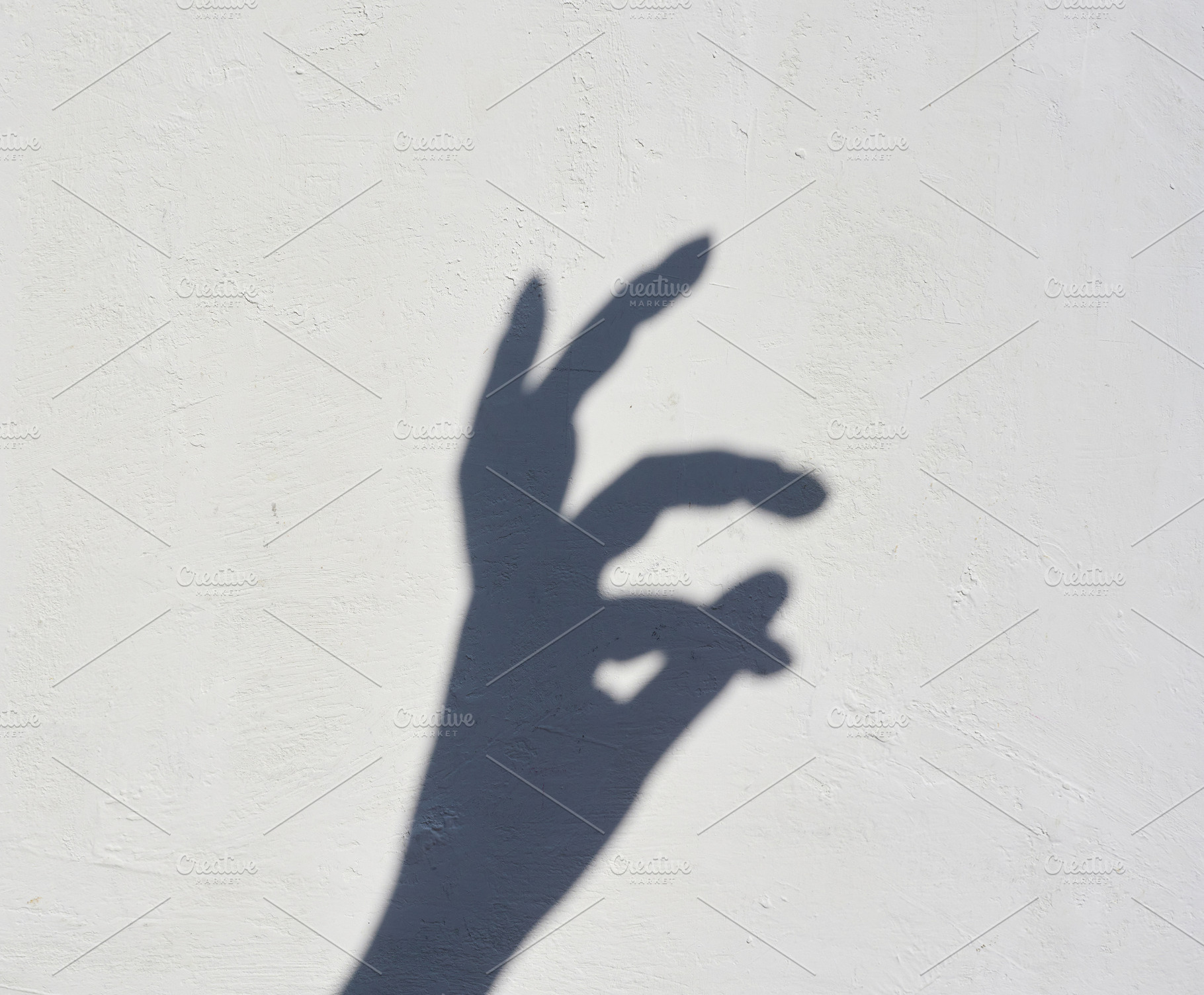 Shadow of a hand on a light wall showing the okay gesture., an Abstract Photo by ndanko