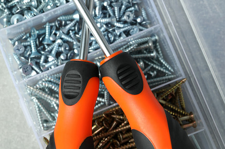 Box with screws and screwdrivers on gray textured background, an Industrial Photo by AtlasStudio PRO