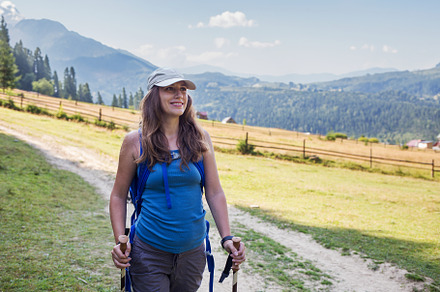 Young woman hiking with poles through a valley in mountains, a Sports & Recreation Photo by serkum