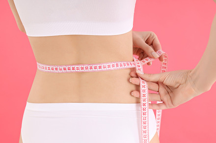 Concept of weight loss with slim young woman on pink background, a Person Photo by AtlasStudio