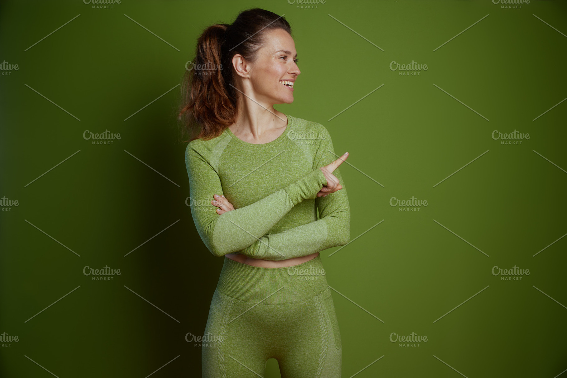 Fit woman in green pointing to the side, a Person Photo by Alliance Images