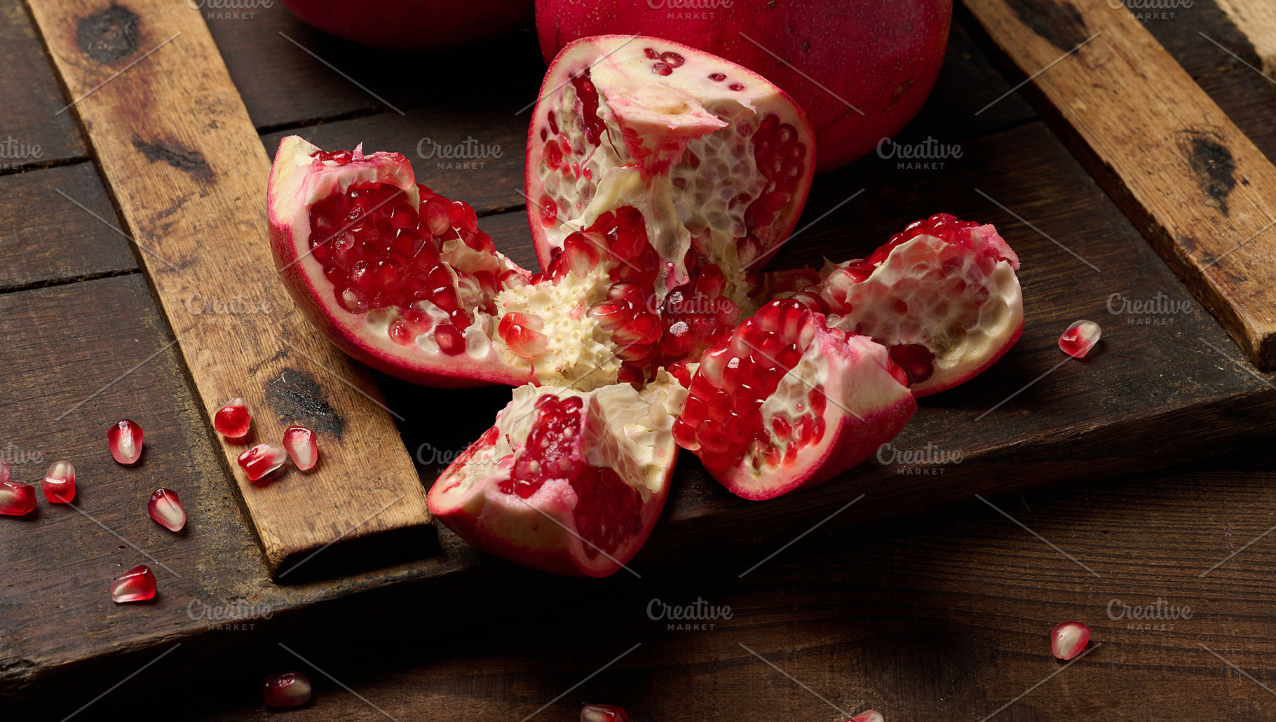 A fresh pomegranate slice with brightly colored seeds on a brown, a Food & Drink Photo by ndanko