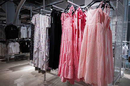 Wide selection of dresses on racks inside a retail clothing store, a Photo by AS photostudio