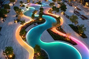 Modern outdoor swimming pool features colorful lights and landscaping at night, a Photo by AlyaAnd