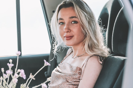 Young woman sitting in the car with flowers., a Person Photo by sabyna75