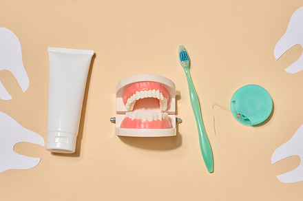 A tube of toothpaste, a toothbrush, dental floss, and decorative