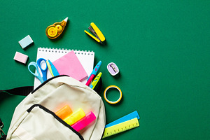 School backpack with colorful stationery on green table. Back to school concept