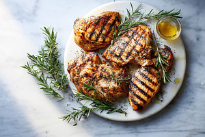Grilled chicken breasts with crisp char marks, fresh rosemary sp, a Photo by Studio ANNA