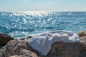 White beach towel resting on sunlit, a Photo by Pavel_design