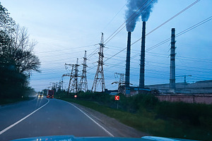 Industrial TPP smokestacks emitting smoke near power lines along a rural road, a Photo by AS photostudio