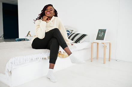 African woman in hoodie sit on the bed at home., a Person Photo by AS photostudio