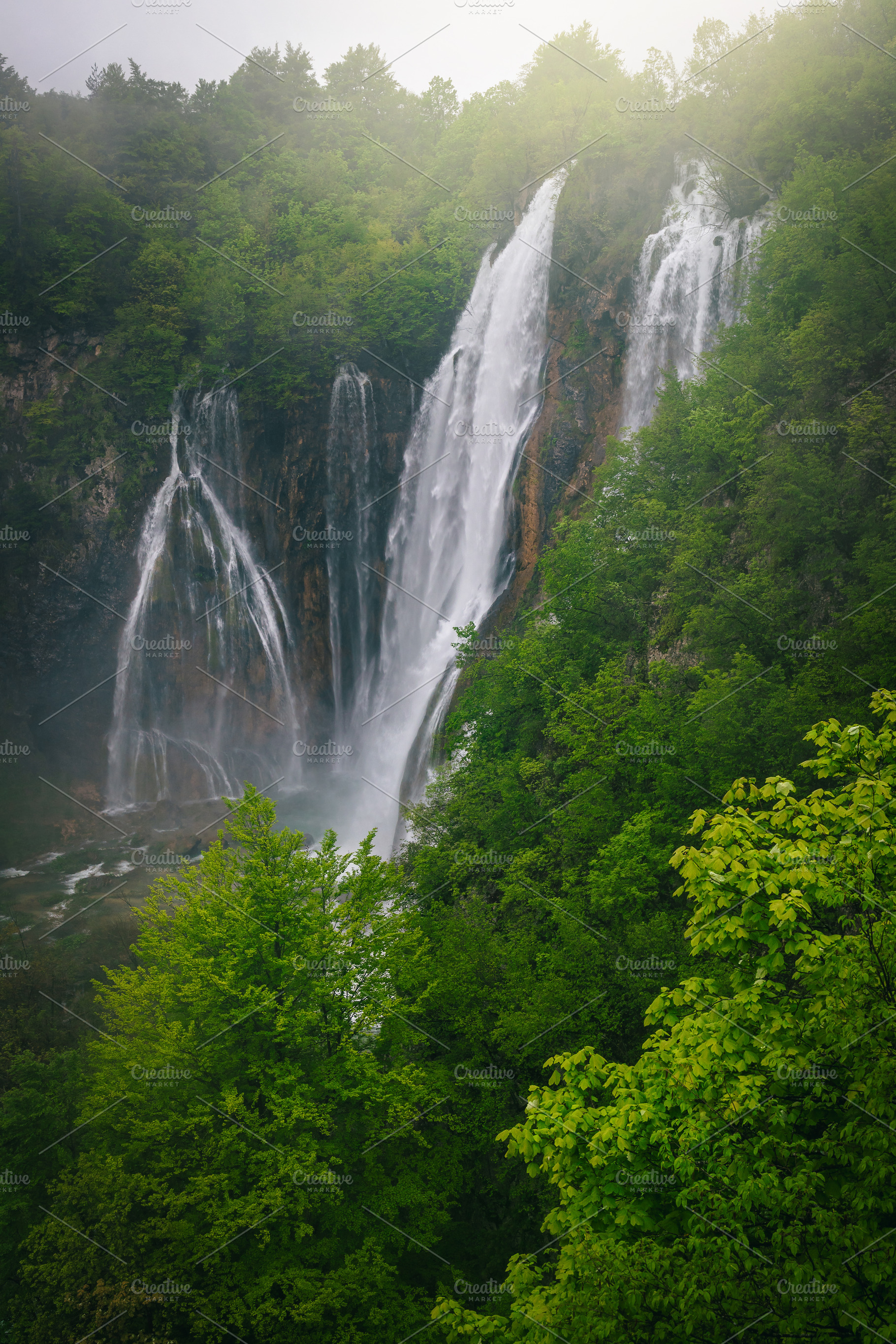 High waterfalls in the green forest, a Nature Photo by Alpine Dreams