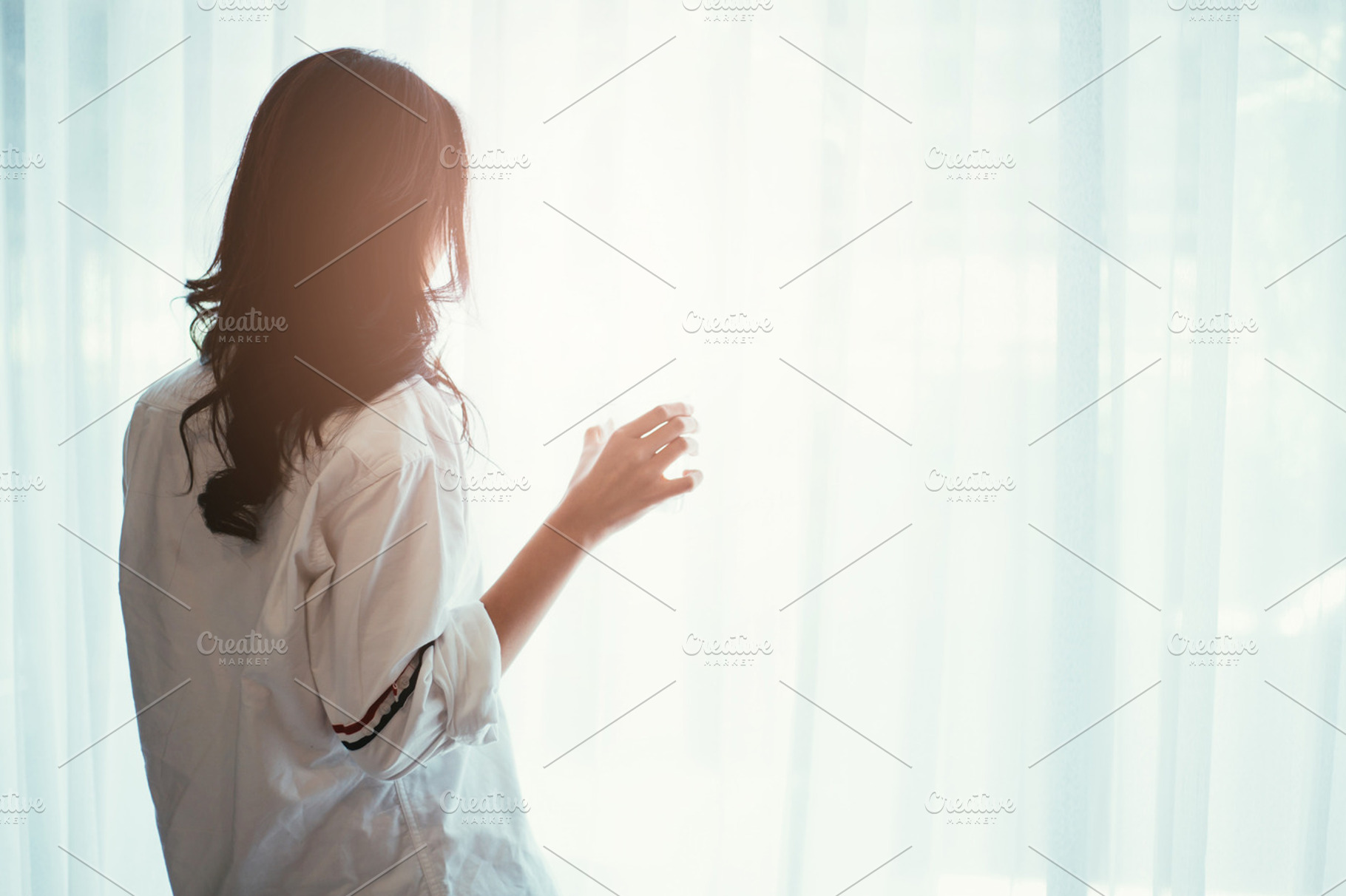 Woman holding a glass of water while looking out of the window - back of silhouette woman, a Person Photo by Twinster Photo