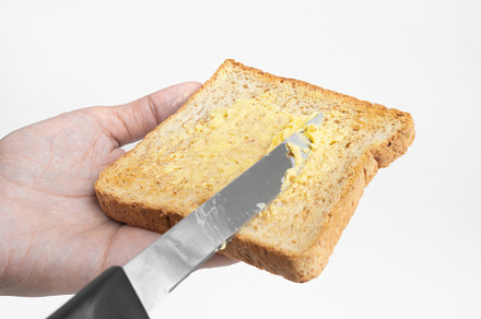 Hands spreading butter on a slice of bread isolated on white bac, a Background Photo by Tampatra