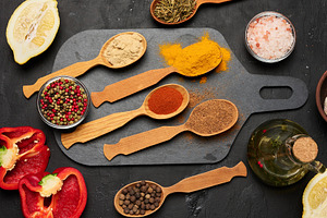 Wooden spoons with ground spices on a black board surrounded by, a Food & Drink Photo by ndanko