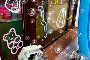 Foam bubble machine producing decorative bubbles outside a colorful storefront, a Photo by AS photostudio