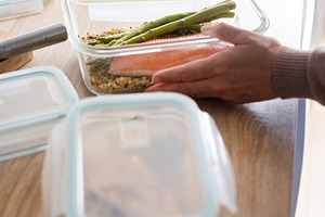 Woman opening a healthy salmon meal prep container in the kitchen, a Food & Drink Photo by etorres69