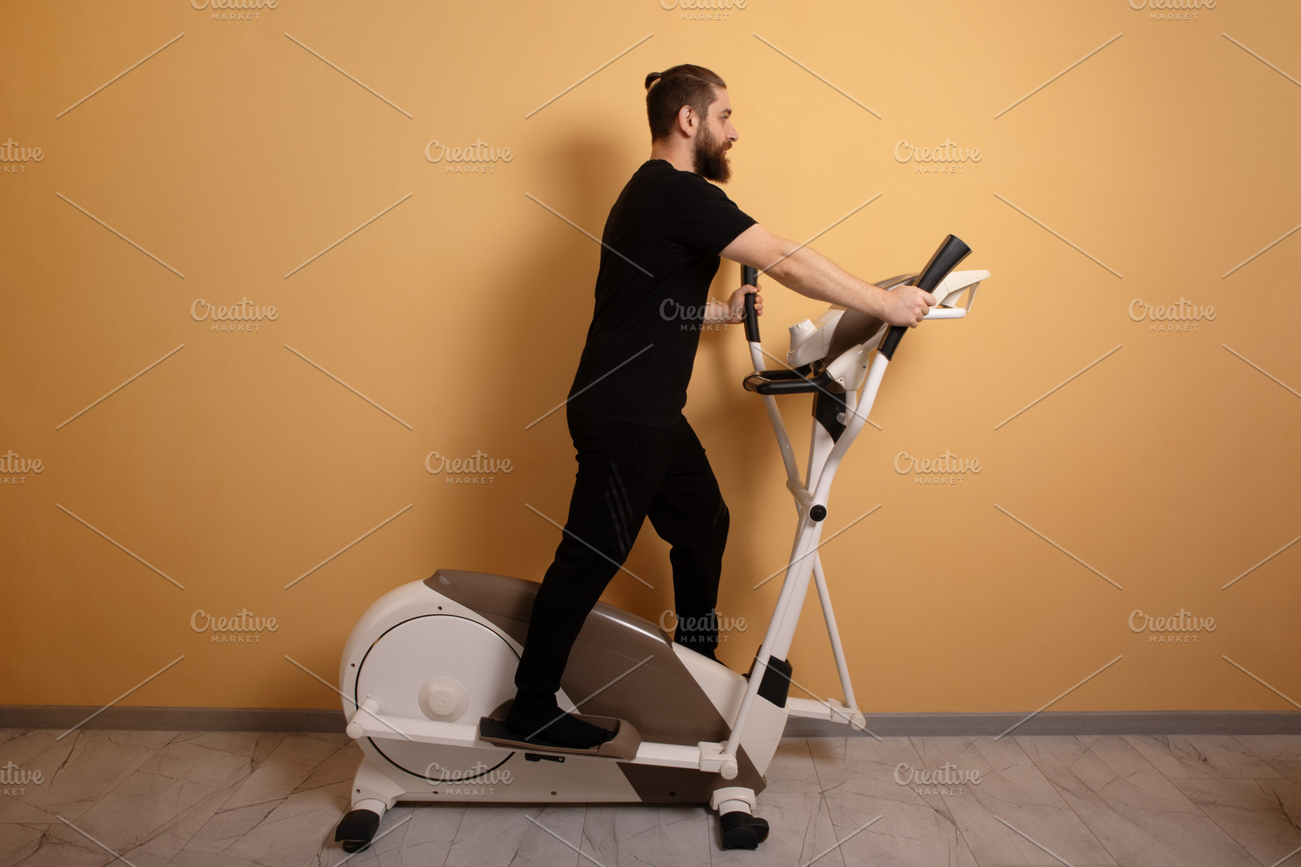 Bearded man in black sportswear using an elliptical trainer agai, a Person Photo by Ales Munt