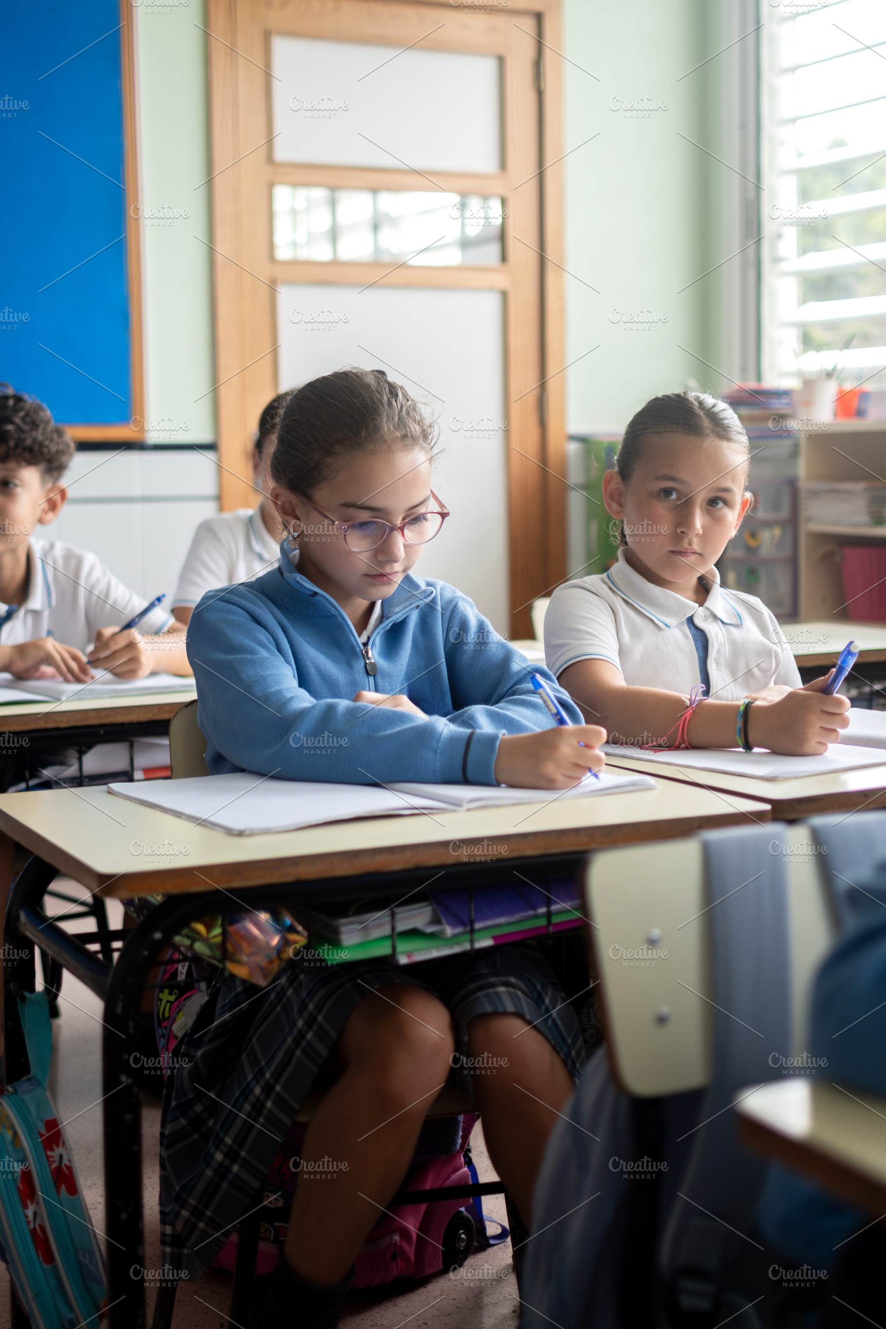 Elementary school students writing in notebooks during a classroom lesson, a School & Education Photo by etorres69