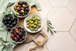Green, black and kalamata olives in bowls on wooden board, a Food & Drink Photo by Olena Rudo