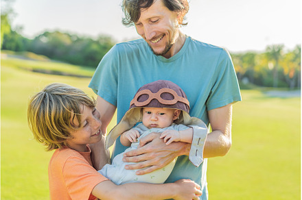 Father, son, and newborn on a meadow