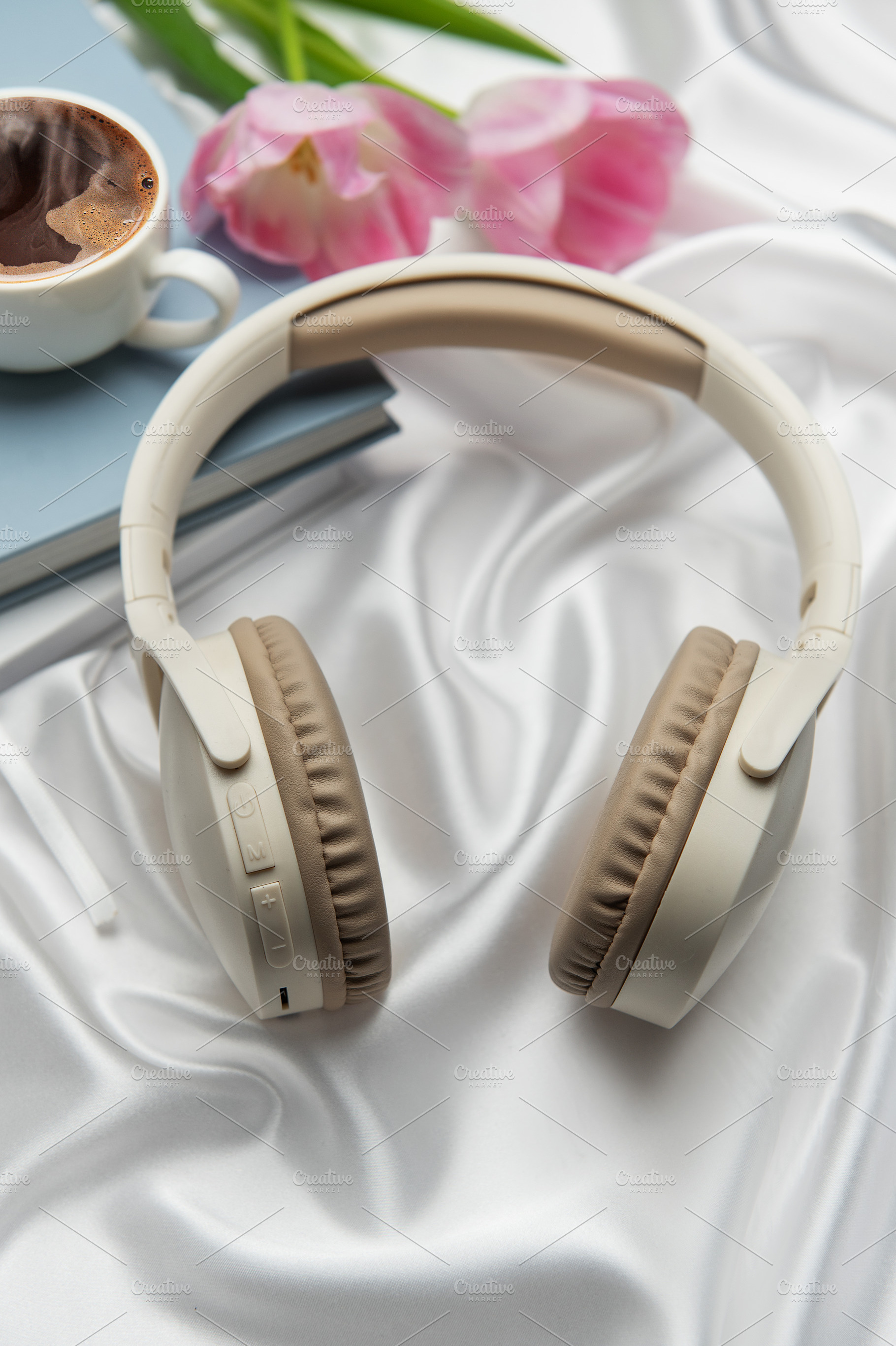 Wireless headphones, coffee, book, and pink tulips resting on wh, a Business Photo by Olena Rudo