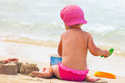 Little girl plays on the shoreline at the beach wearing a hat., a Person Photo by Antonio Gravante Market