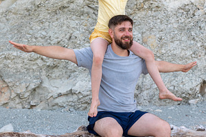 Smiling father with daughter on shoulders, both with outstretched arms, enjoyin, a Person Photo by Ales Munt