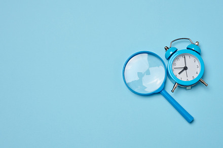 Alarm clock and magnifying glass on a blue background, symbolizi, a Business Photo by ndanko