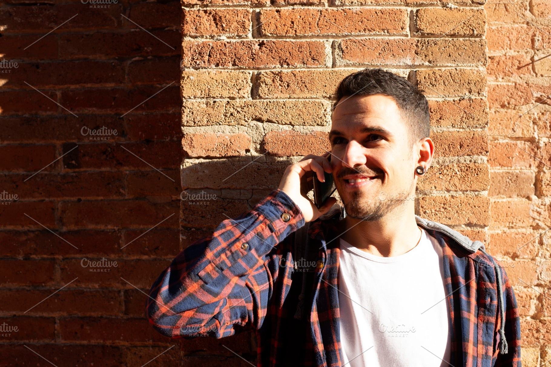 Young caucasian man smiling while talking on smartphone outdoors, a Person Photo by RF Images