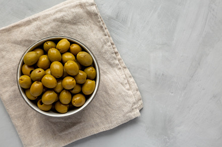 Marinated Green Pitted Olives in a Bowl, top view. Flat lay, ove, a Food & Drink Photo by LiudmylaChuhunova