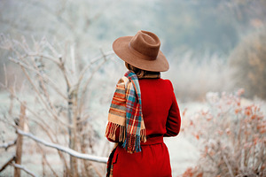 Woman in hat and red coat in winter countryside