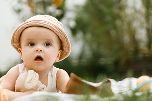 Beautiful happy baby in hat lying on blanket and playing with to, a Person Photo by Sonjachni