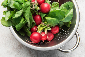 Fresh radishes with green tops in colander, a Food & Drink Photo by Olena Rudo