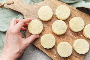 Hand preparing syrniki cottage cheese pancakes on wood, a Food & Drink Photo by Olena Rudo