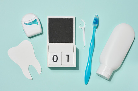 Blue toothbrush, white tube of toothpaste, dental floss in blue
